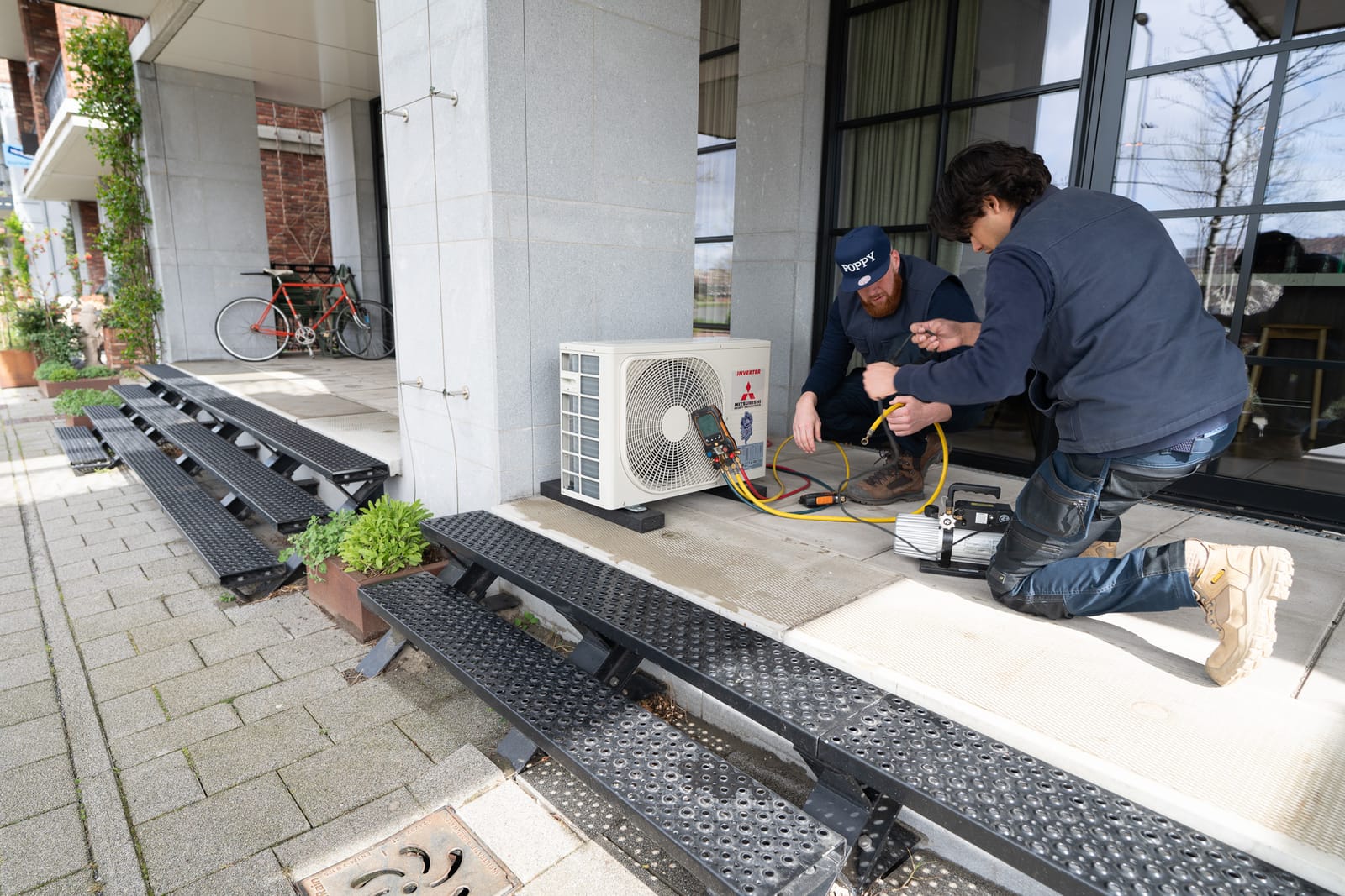 Twee monteurs sluiten een buitenunit aan op locatie