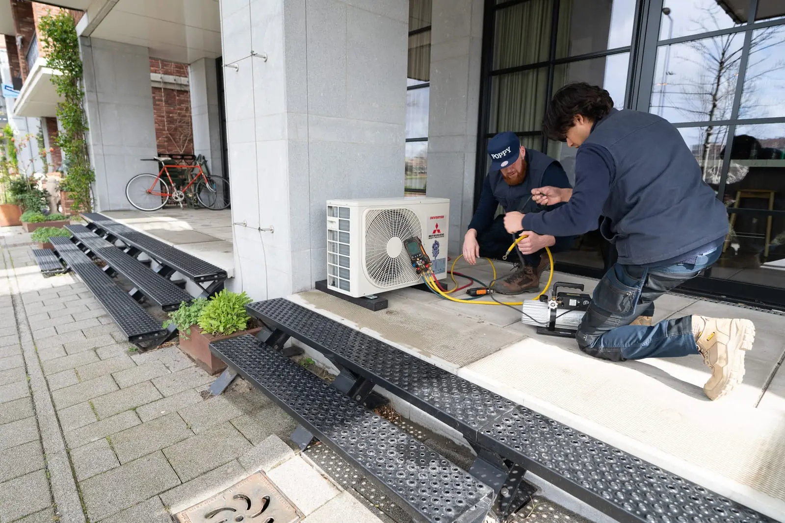 Twee monteurs sluiten een buitenunit aan op locatie