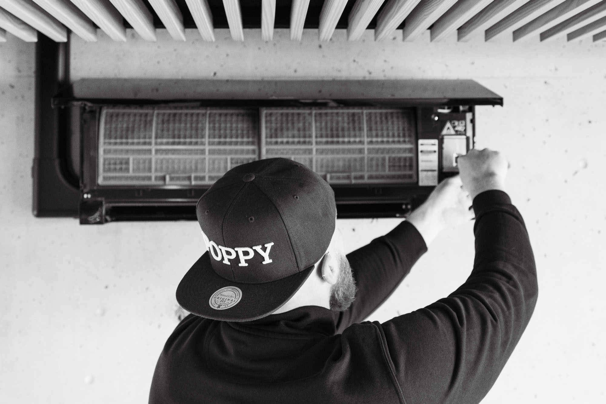 Monteur met Poppy-pet opent het filterpaneel van een wandunit