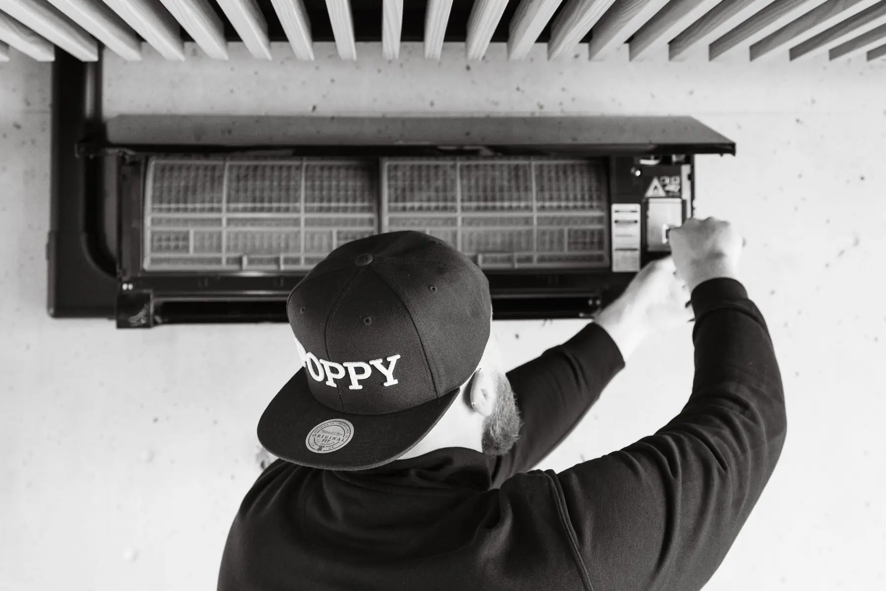 Monteur met Poppy-pet opent het filterpaneel van een wandunit